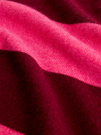A close-up of a soft knit fabric with draped folds in bright pink and deep burgundy.