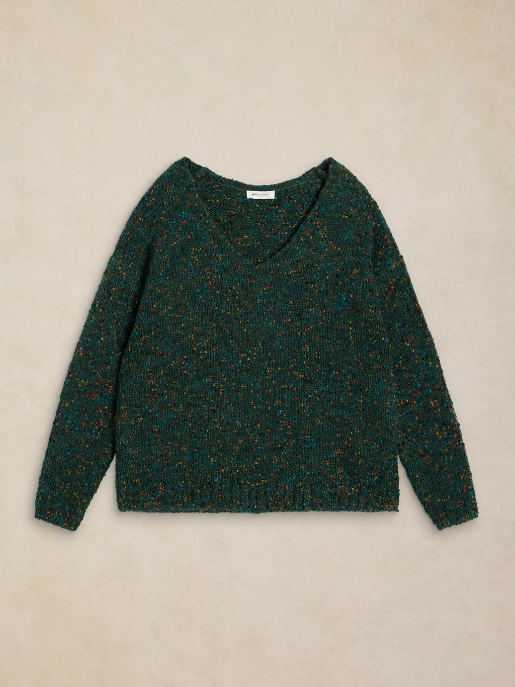 A dark green marled knit sweater with a wide V-neck and long sleeves, laid flat on a textured beige background.