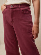 Maroon pants worn by a person on a beige background
