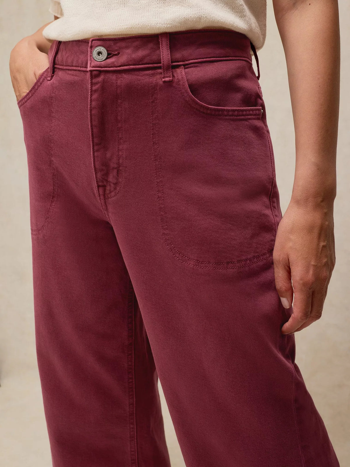 Maroon pants worn by a person on a beige background