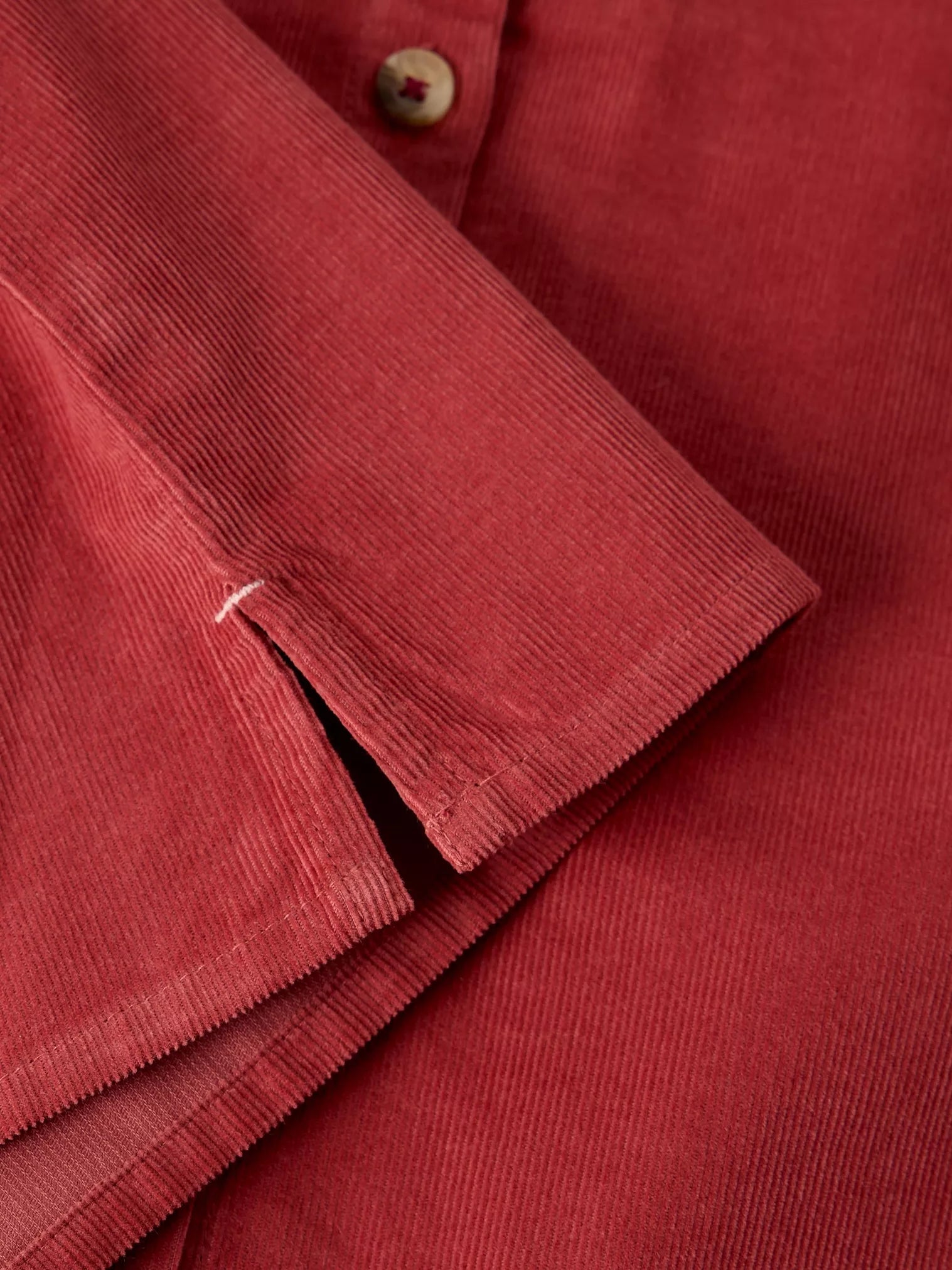 Close-up of LANA dusty pink BABY CORD TOP showing the textured fabric, button, and folded cuff detail.