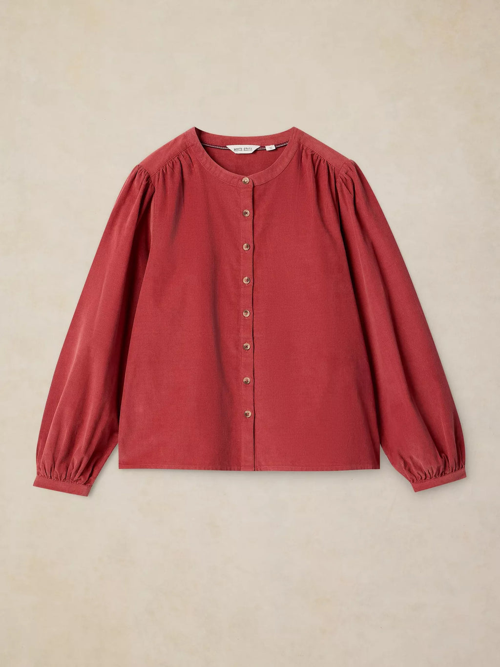 LANA dusty PINk BABY CORD TOP with gathered puff sleeves and a button-up front, laid flat against a textured beige background.