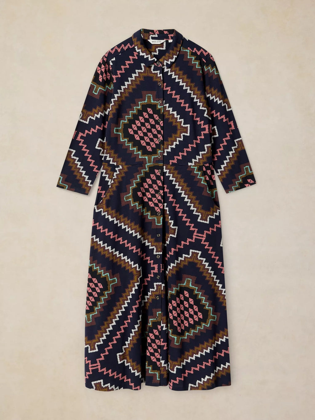 Rua Jersey Dress in Navy Multi with a geometric Southwestern pattern in navy, pink, brown, white, and green, laid flat against a light beige background.