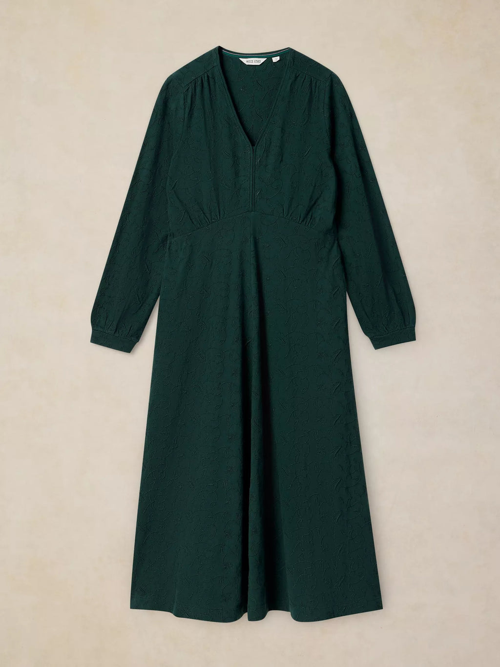 A dark forest green long-sleeve midi dress with a V-neckline and gathered waist details, displayed flat against a textured beige background.