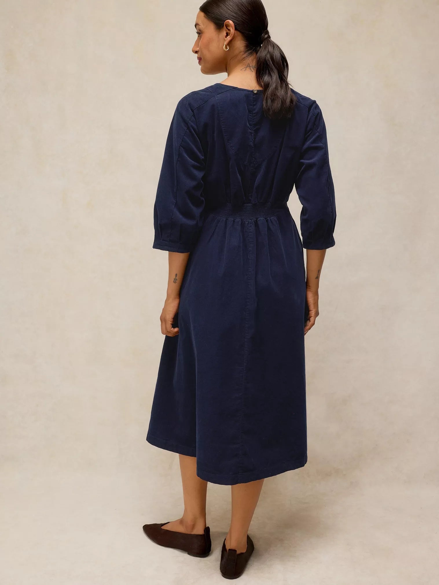 Woman wearing a navy blue dress against a beige background