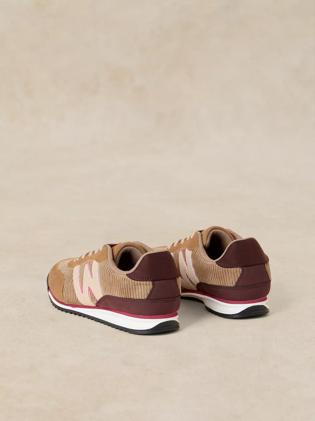 A pair of A Lucy Trainer sneaker in Natural multi shown from the back three-quarter view, featuring a beige and dark brown knit upper with light pink 'W' logos and a white midsole.