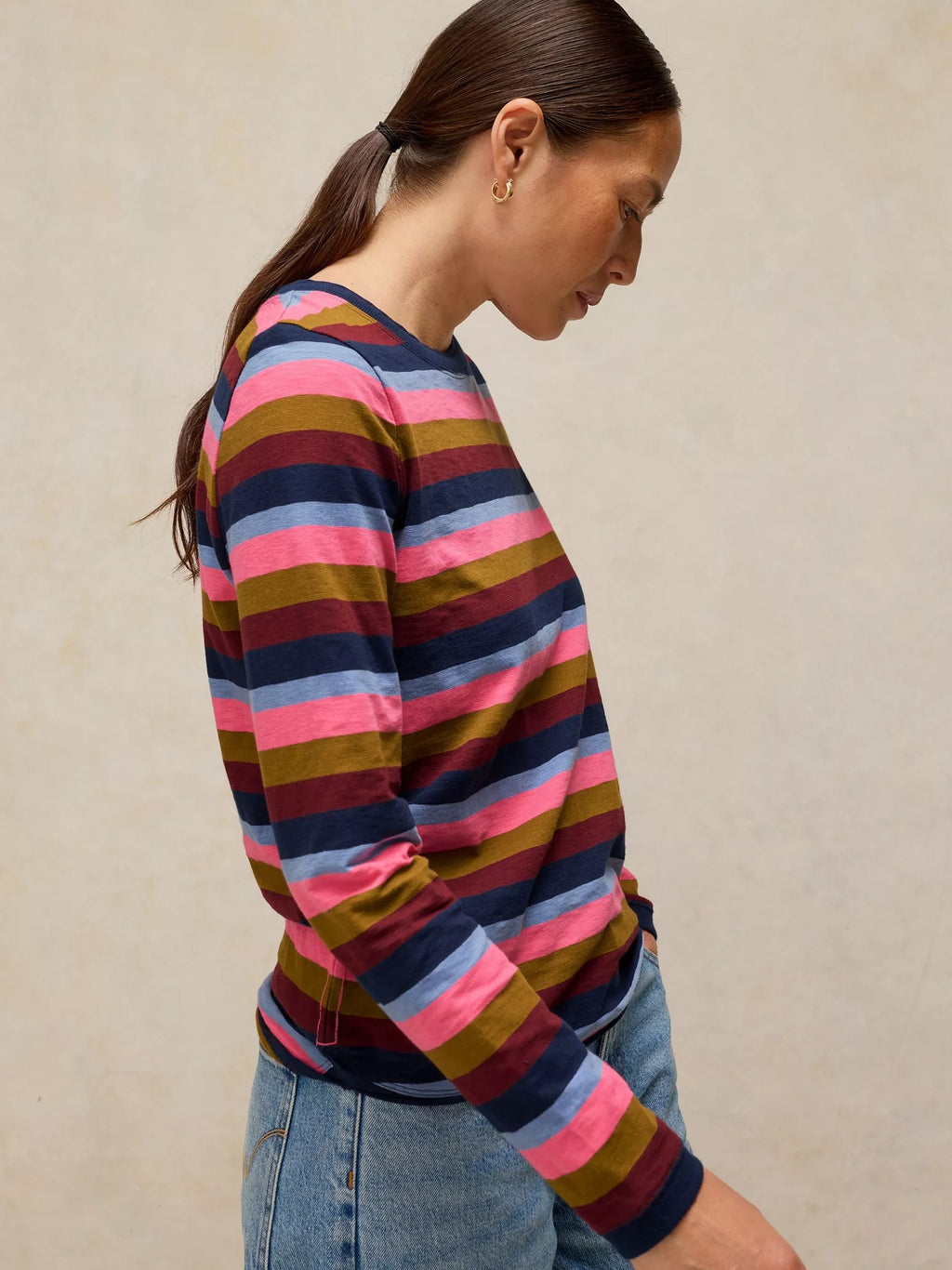 Woman wearing a CLARA STRIPE LS TEE
in PINK MULTI against a beige background