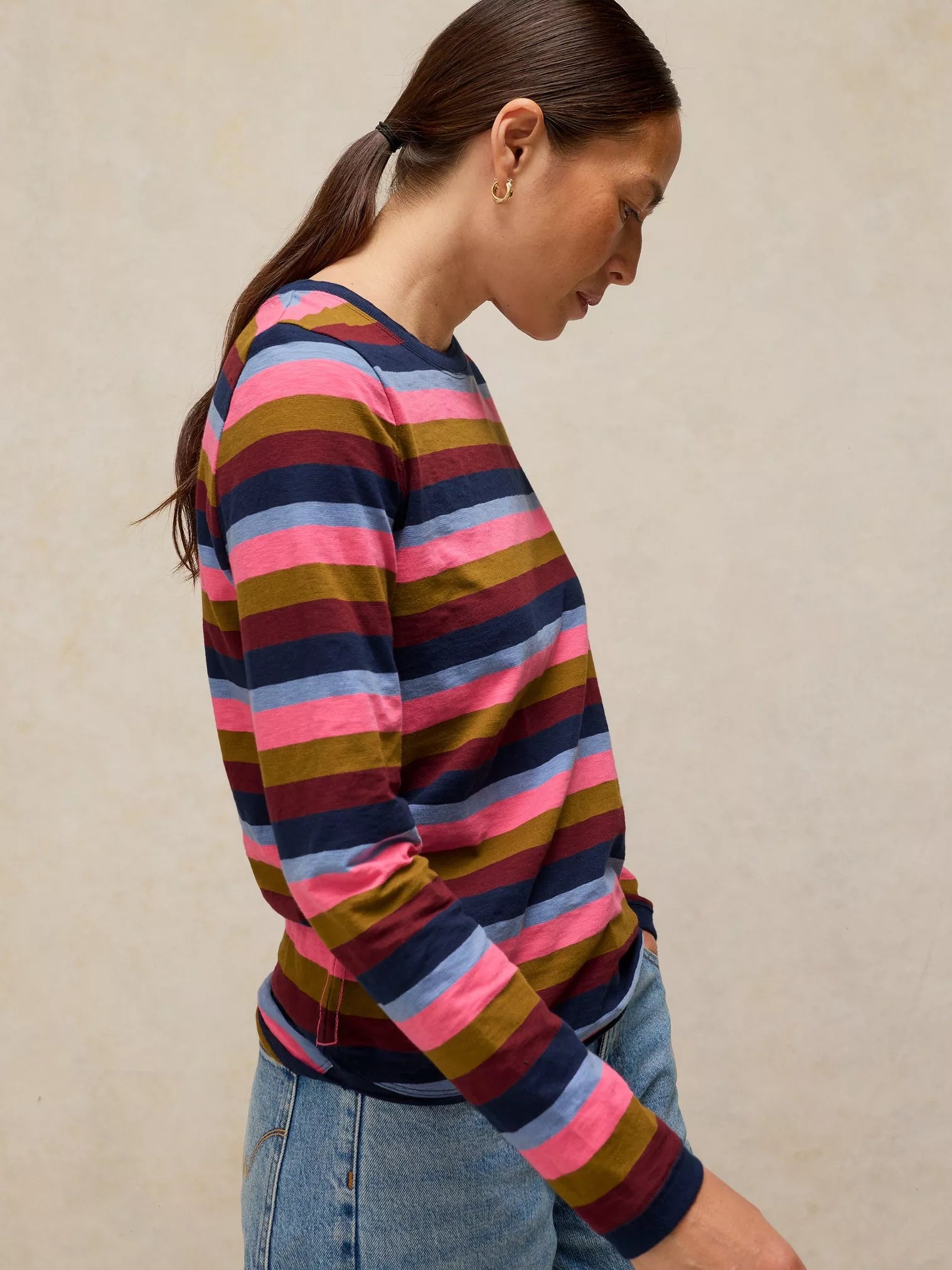 Woman wearing a CLARA STRIPE LS TEE
in PINK MULTI against a beige background