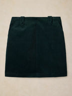 A dark forest green mini skirt with belt loops and side pockets, laid flat on a light beige textured background.