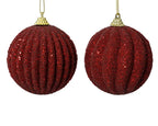 Two red glittery Christmas ball ornaments on a white background