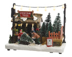 Decorative Christmas scene with a tree stand and people around it, featuring a 'Christmas Trees' sign