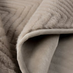 Close-up of a soft, plush throw blanket in a warm light beige or Ellis Throw in Mink - showing quilted texture on one side and a smoother fabric underside on the other.