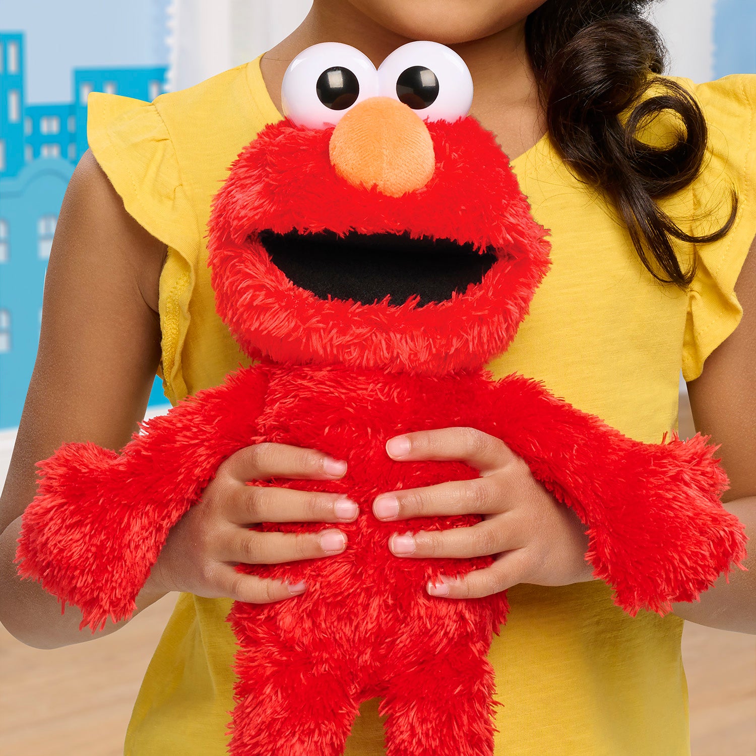 Person holding tickle me elmo with large eyes and a yellow shirt.