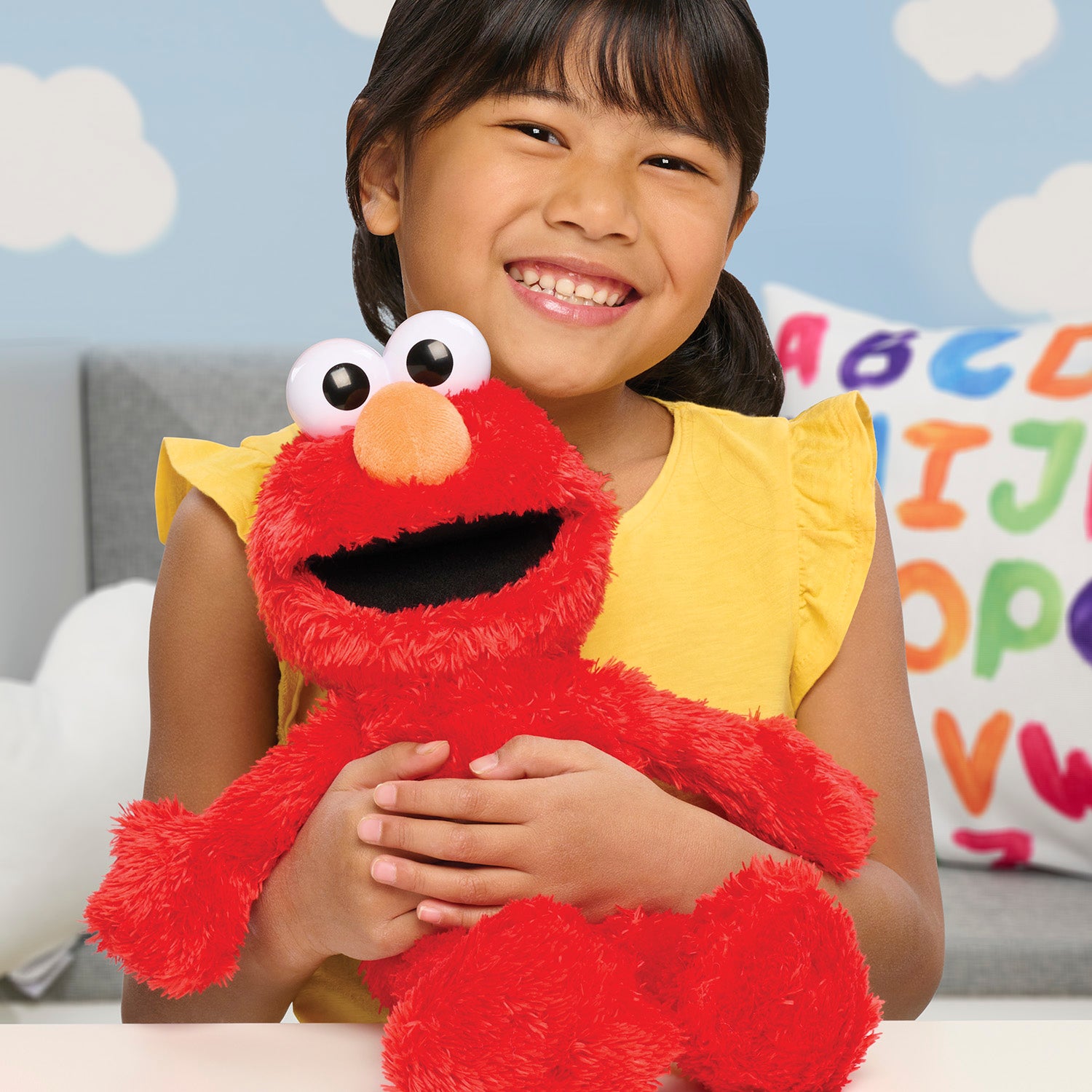 Child holding a red plush toy with googly eyes in a colorful room