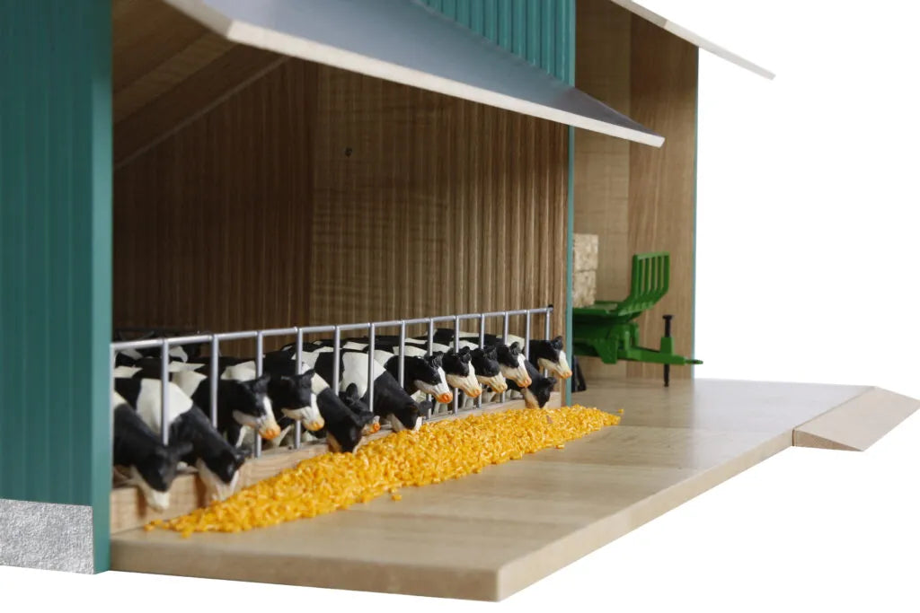 Model of cows in a barn with a green roof and yellow feed.