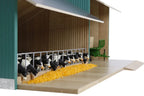 Model of cows in a barn with a green roof and yellow feed.