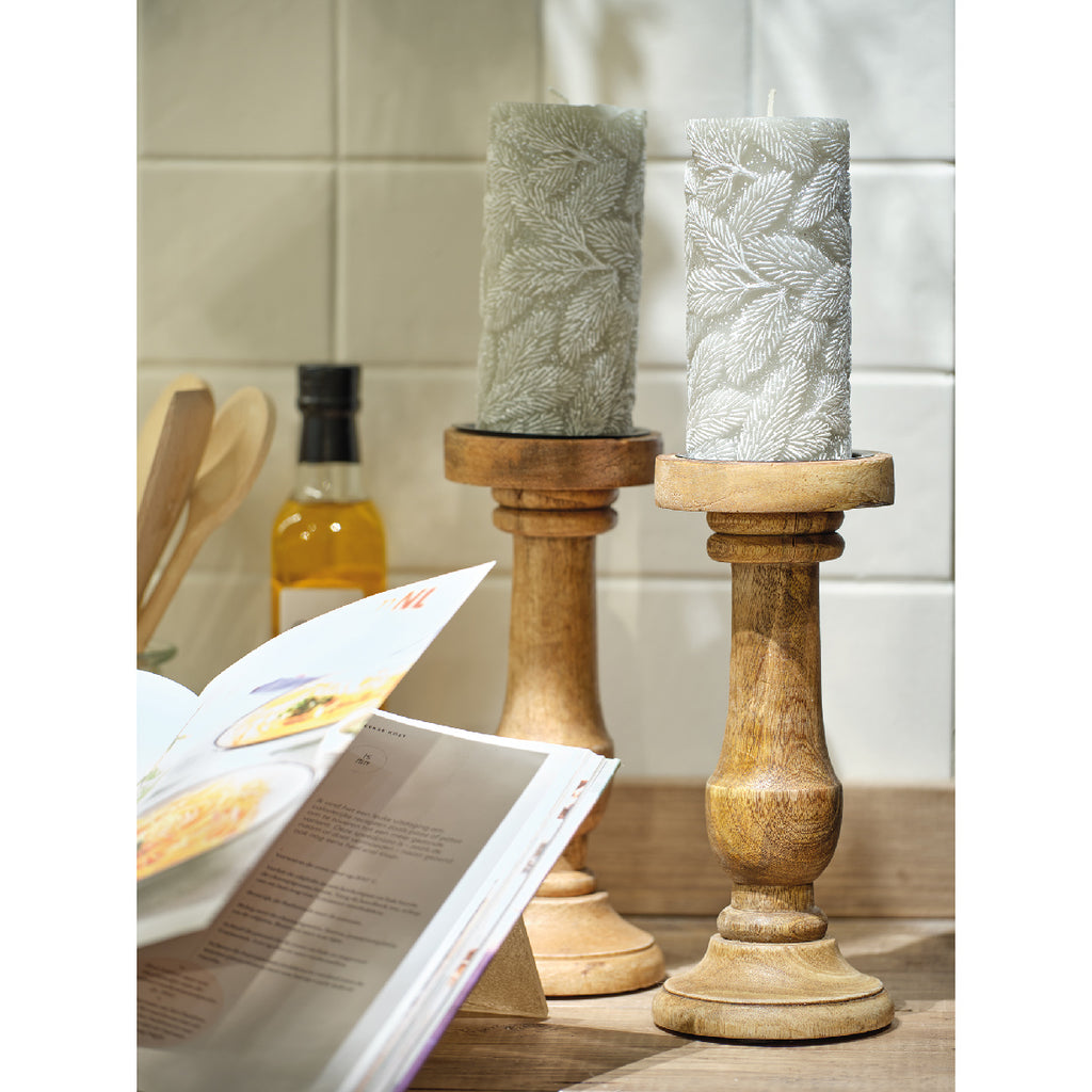 Two textured candles on wooden stands with a magazine open in the foreground.