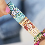 Colorful wristband with cartoon character design held by a hand against a blurred background