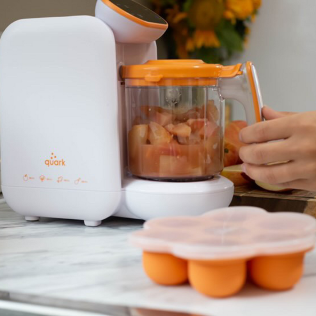 Quark baby food maker with fruits inside on a marble surface