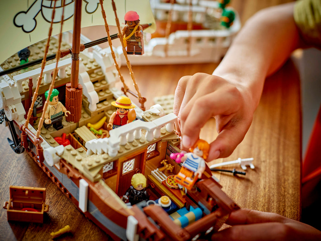 Close-up of a hand arranging LEGO figures on a pirate ship model.