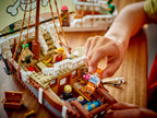 Close-up of a hand arranging LEGO figures on a pirate ship model.