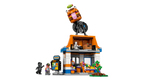 LEGO set with a small building, characters, and a vehicle on top against a white background