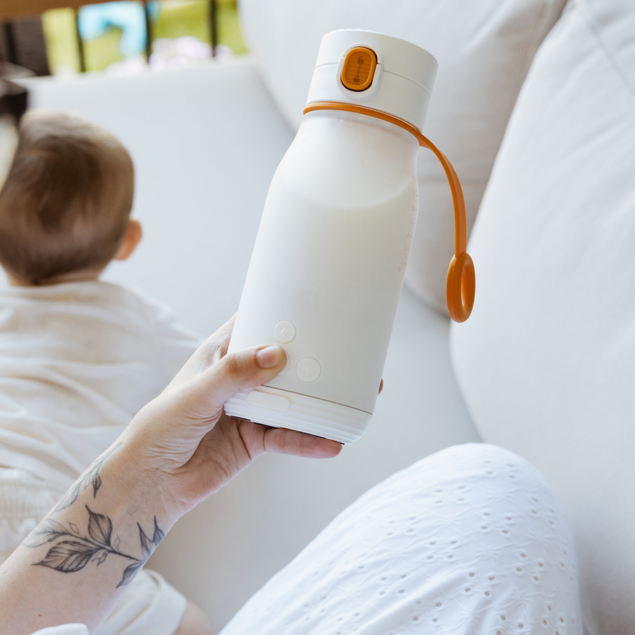 Person holding a white and orange water bottle with a child in the background