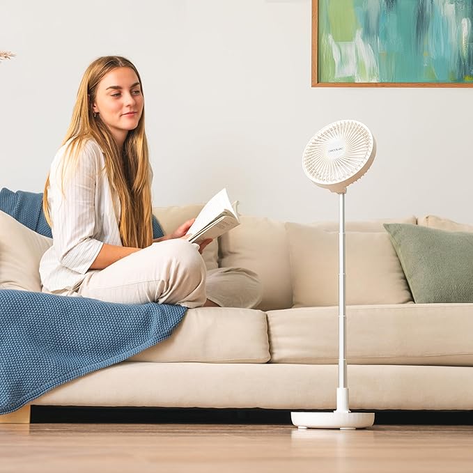 Woman reading a book on a couch with a Cecotec EnergySilence 800 Foldable Fan in White near by