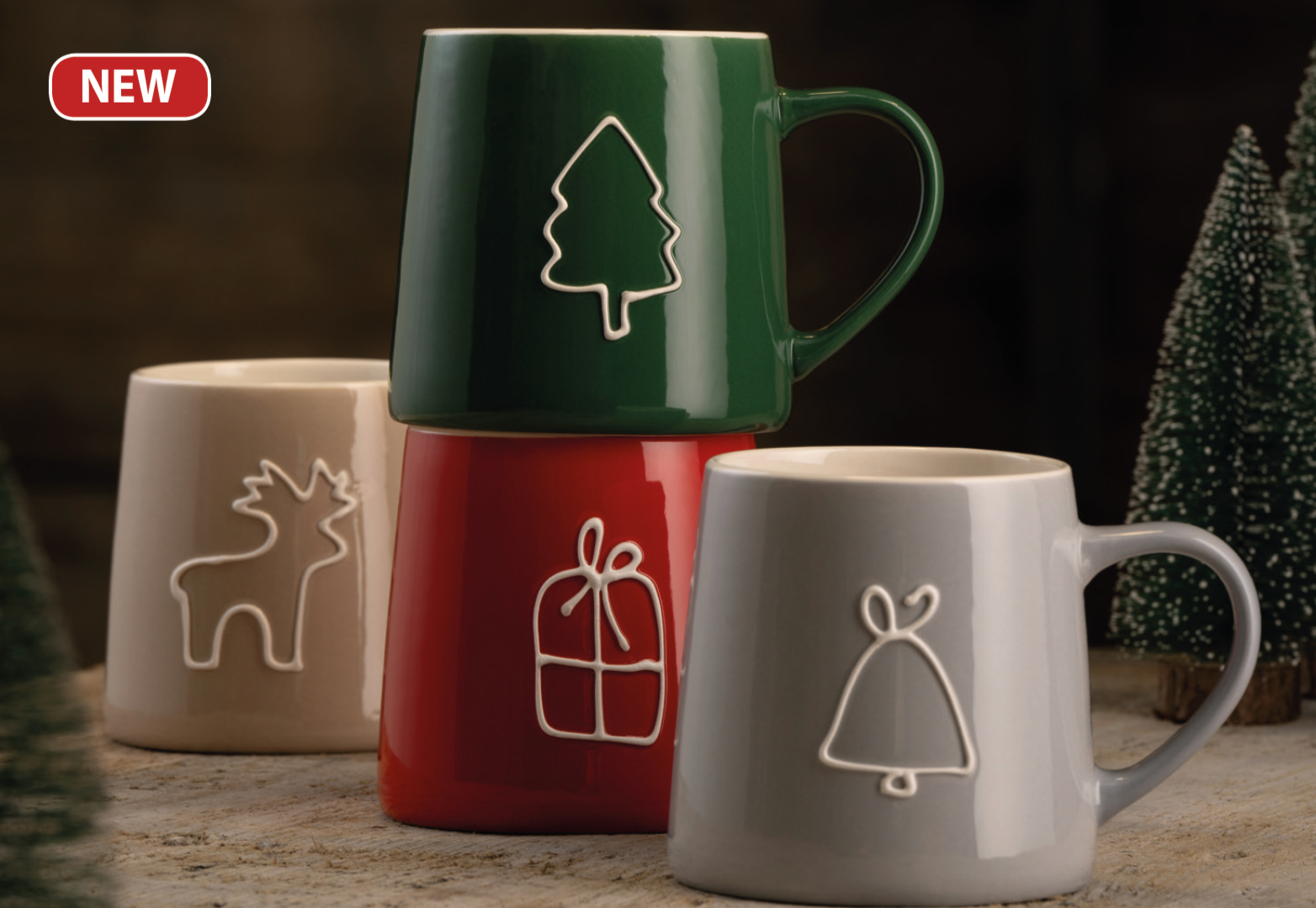 Set of four mugs with Christmas-themed designs on a wooden surface.