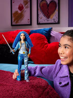 Child holding a doll with blue hair and outfit in front of a colorful couch.