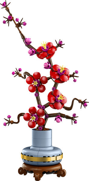 Decorative model of a cherry blossom branch with red flowers in a vase on a white background