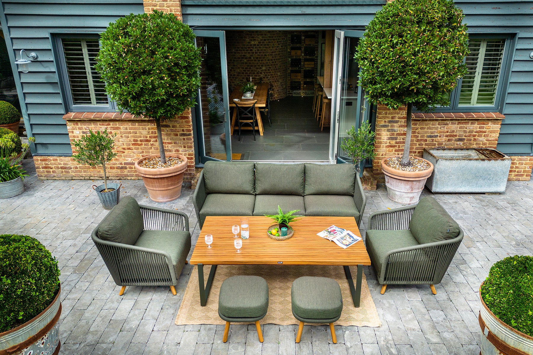 Eden 3 Seat Lounge Set Outdoor patio area with a wooden table, chairs, and potted plants.