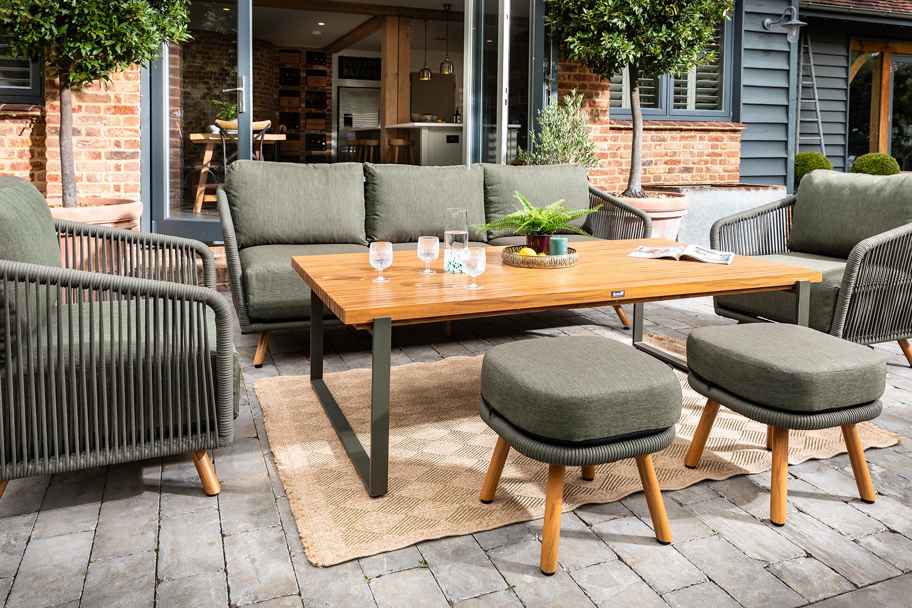 Eden 3 Seat Lounge Set Outdoor patio set with green sofa, chairs, and ottomans around a wooden table.