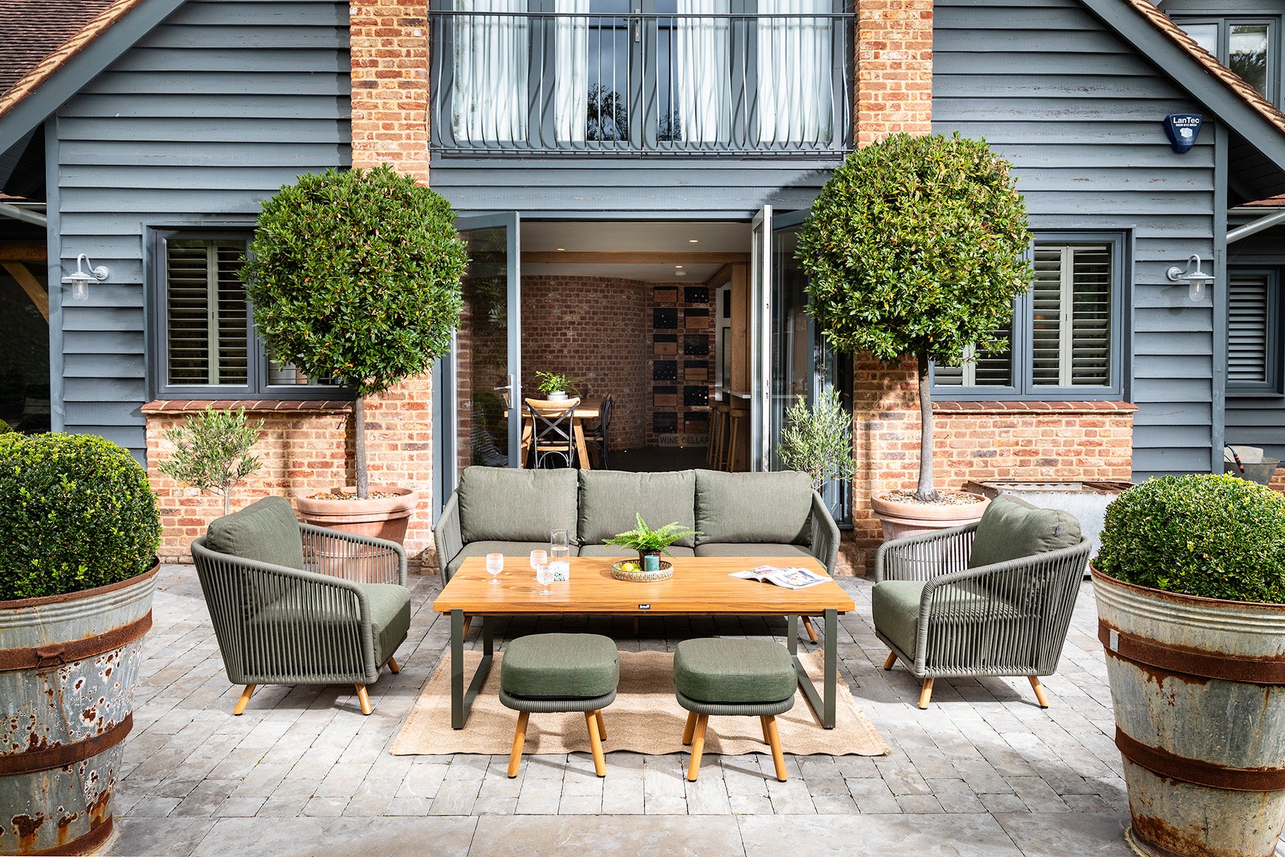 Outdoor patio area with furniture and plants in front of a house frontal view of the Eden 3 Seat Lounge Set