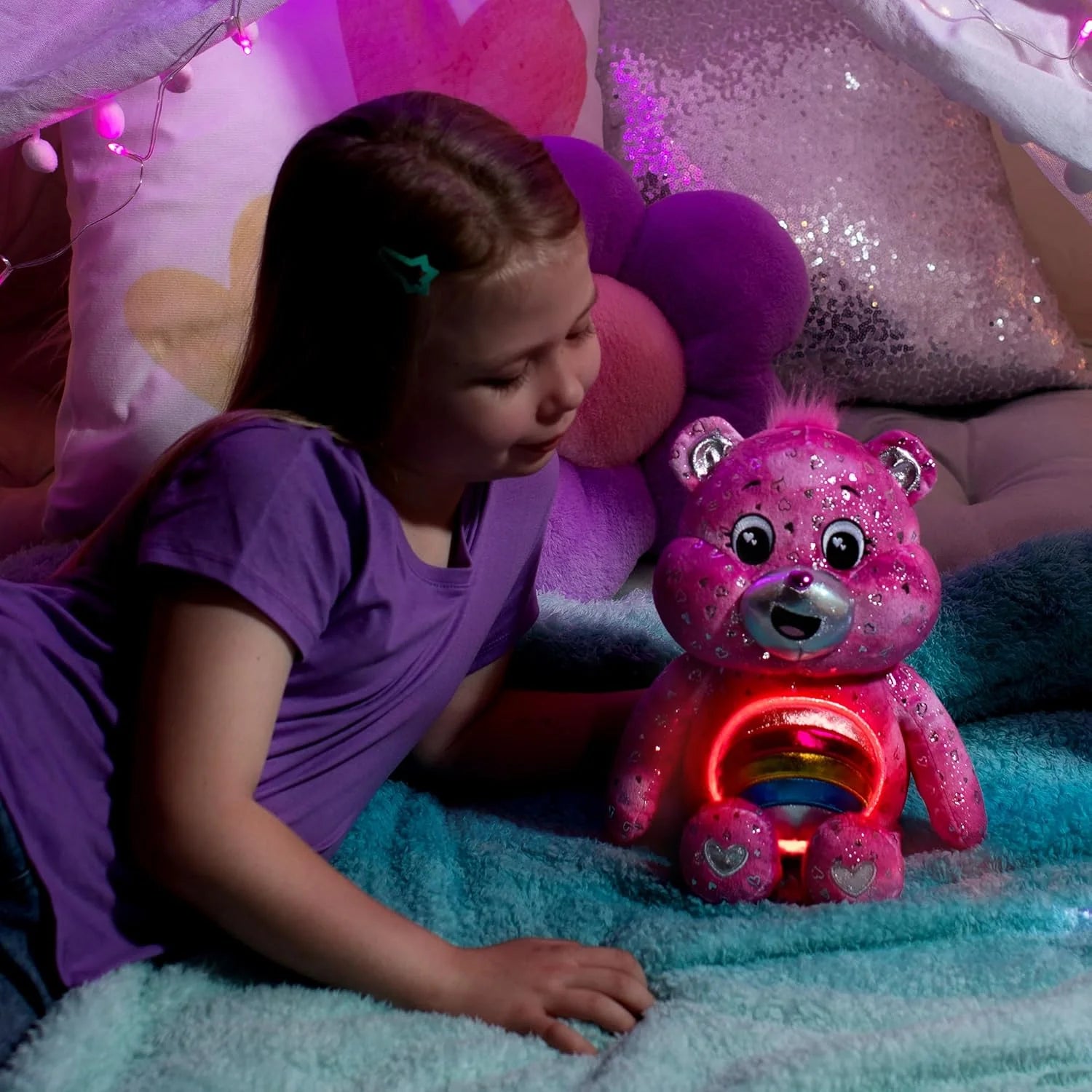 Child playing with a glowing pink toy bear in a cozy room.