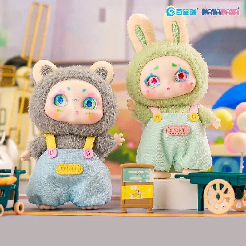 Two plush toys, one gray and one green, with colorful eyes and outfits on a blurred background.