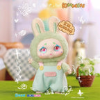 Toy figure in a green outfit with bunny ears, standing on a grassy surface with a blurred background.