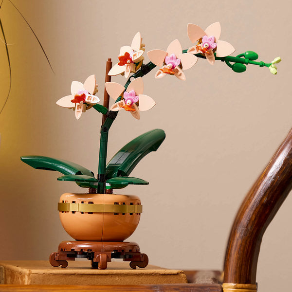LEGO model of an orchid plant on a wooden surface with a neutral background