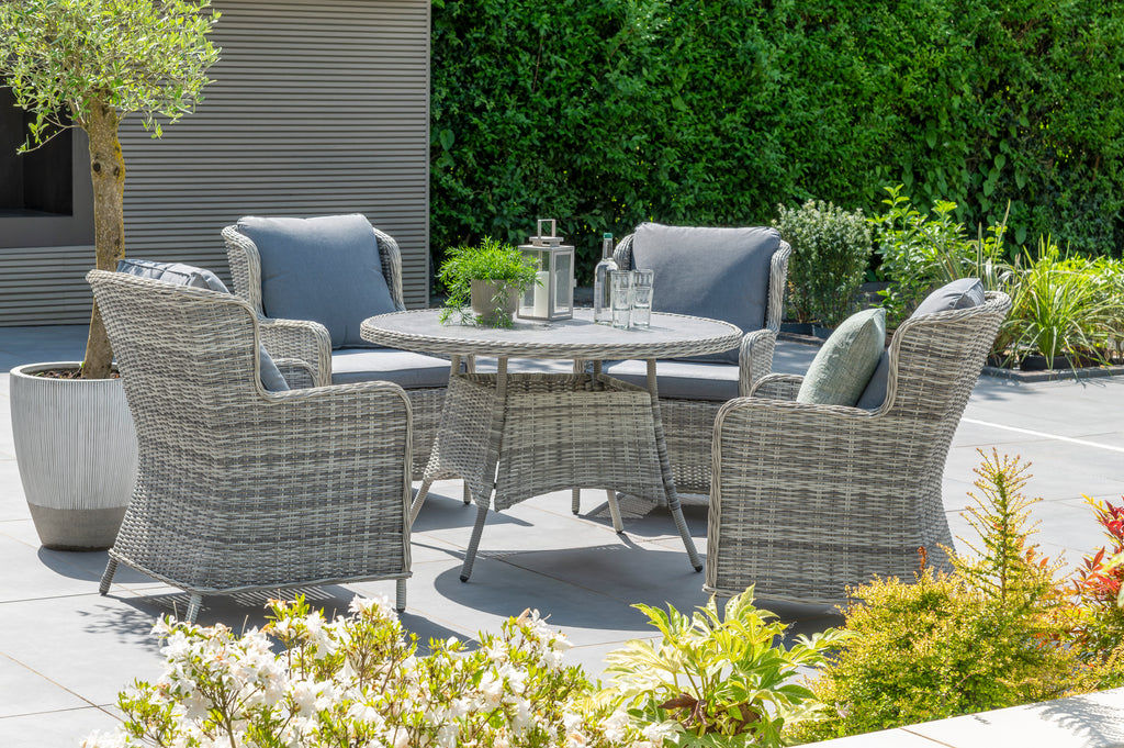 Outdoor patio set with chairs and a table in a garden setting