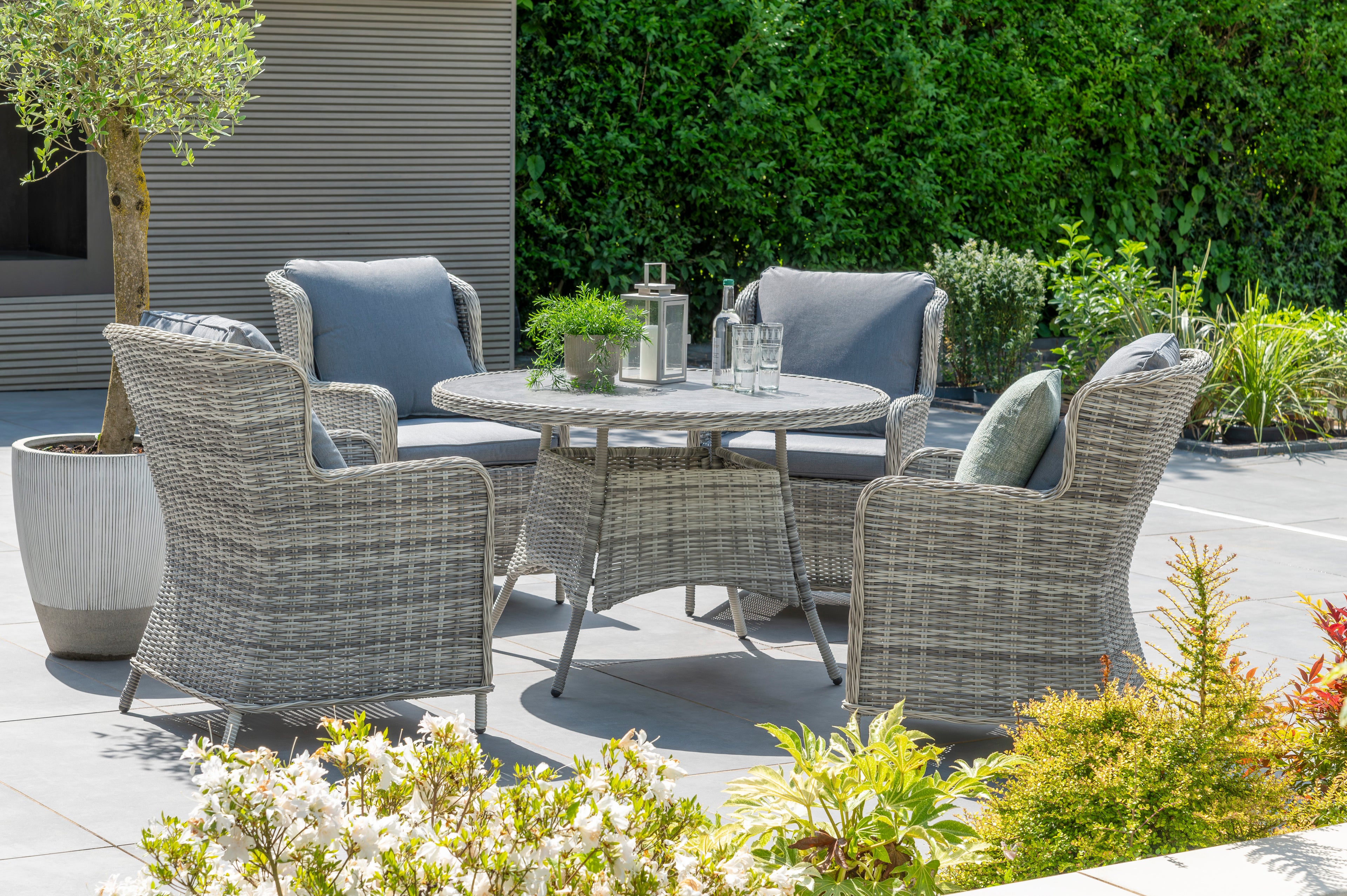 Outdoor patio set with chairs and a table in a garden setting