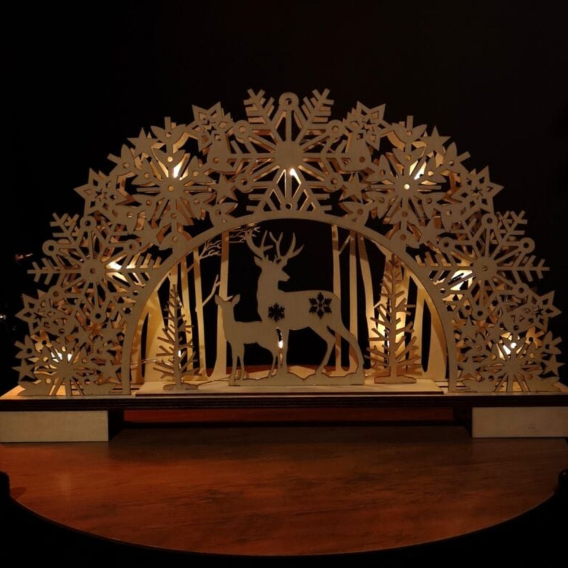 Decorative arch with cut-out designs of deer and snowflakes on a dark background