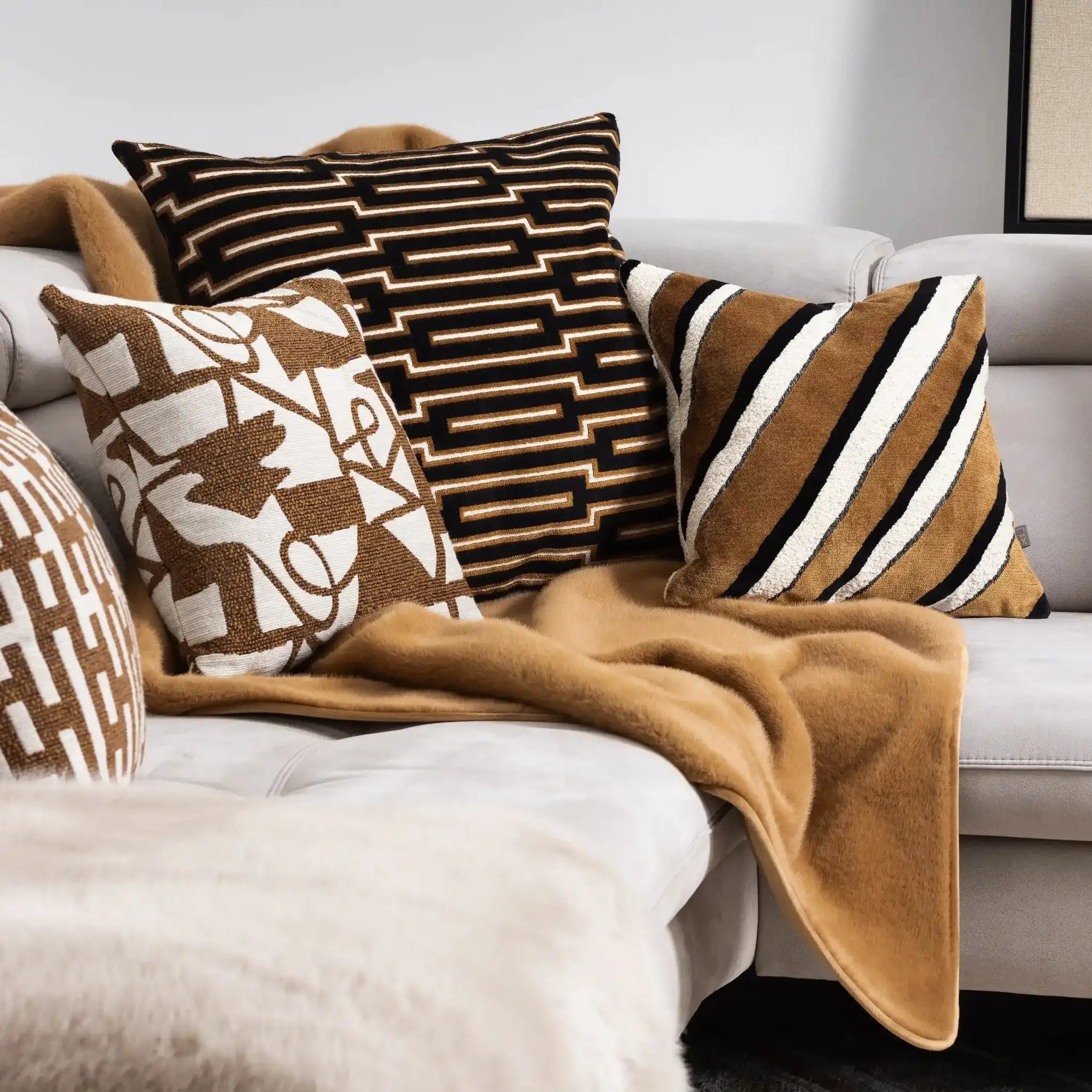 Decorative pillows and Ralph Throw in Cognac on a sofa with a neutral color scheme