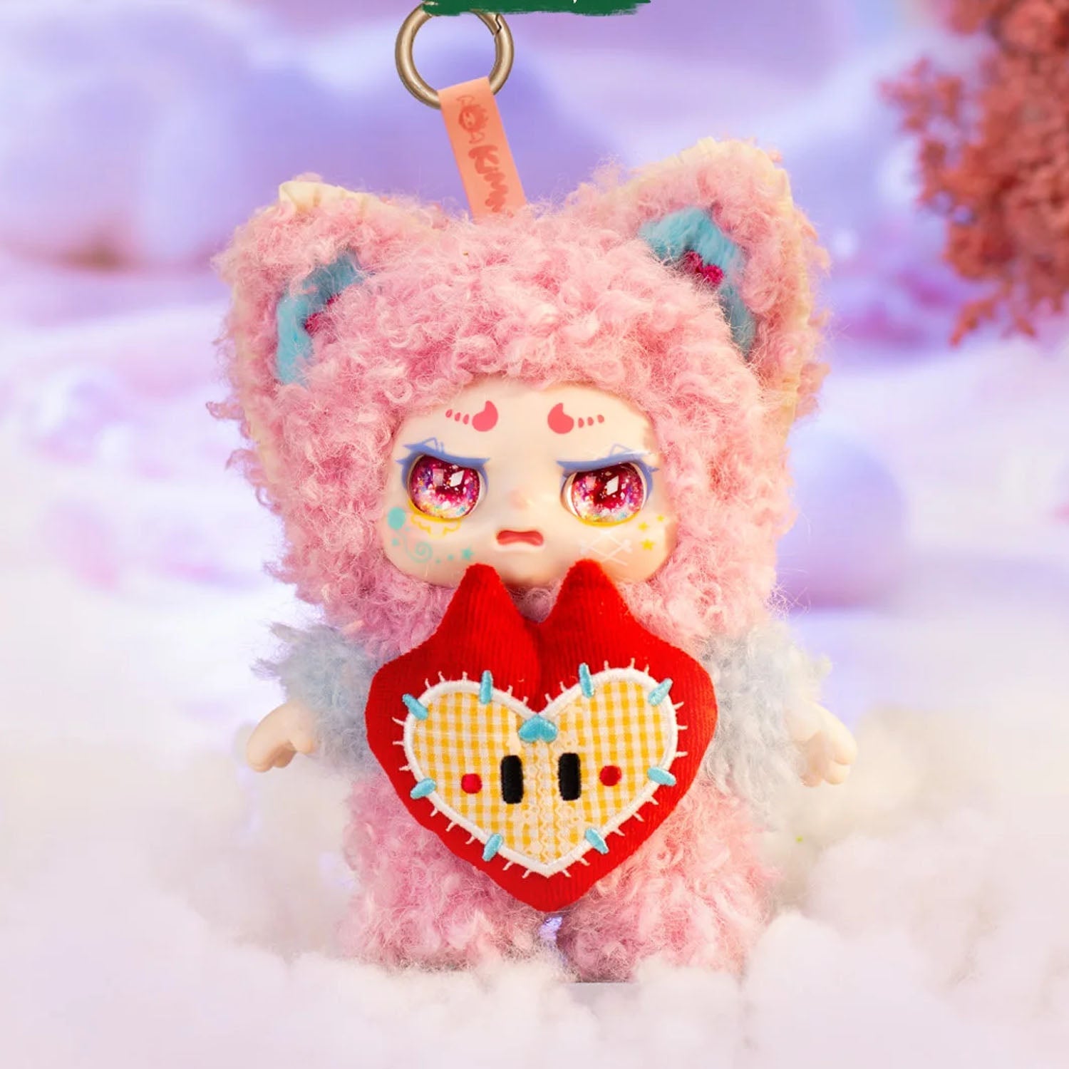 Plush toy with pink fur and a red heart, set against a soft focus background.