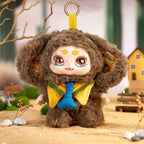 Plush toy with a bear-like design wearing a yellow outfit with a blue bow tie, standing on a sandy surface with a blurred natural background.