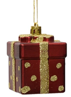 Red gift box ornament with gold glitter ribbon and polka dots on a white background