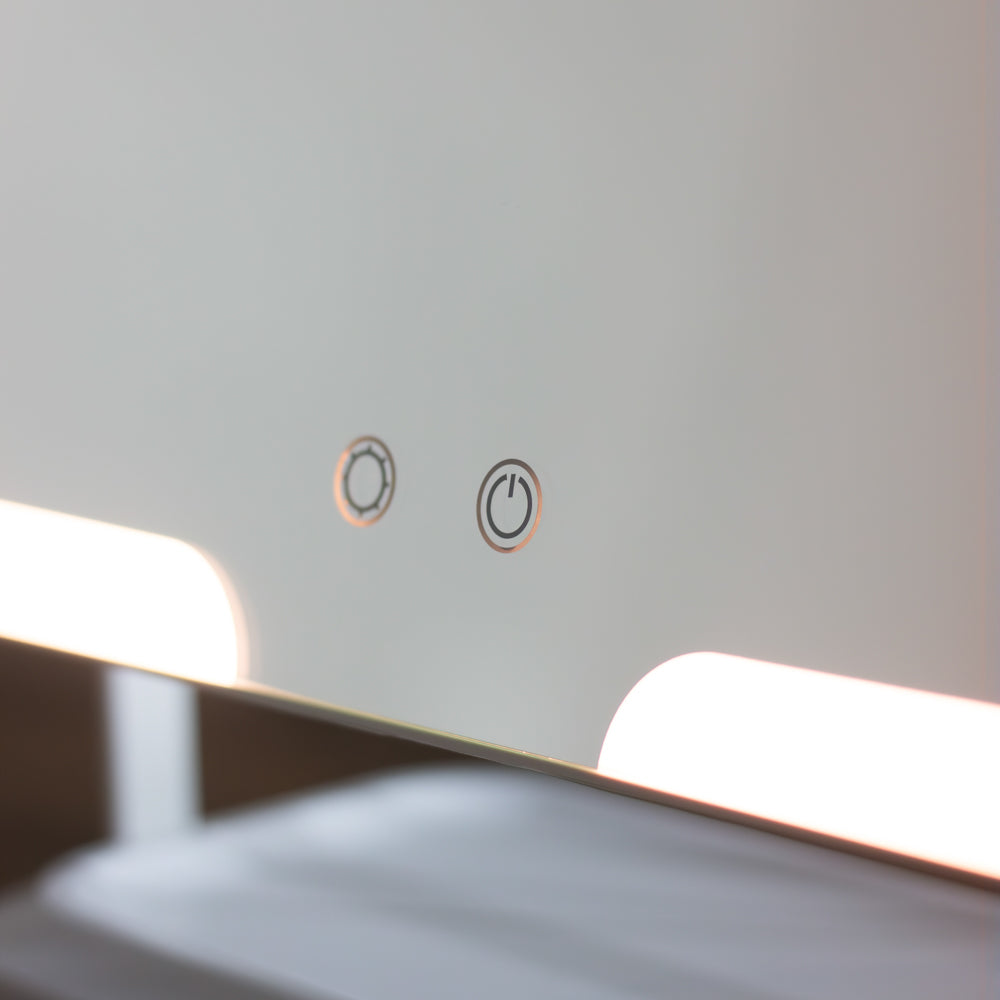 Close-up of a modern lighted Hollywood Rechargeable Portable Mirror showing two control icons on its reflective surface, with bright white light glowing from the bottom edge.