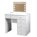 White vanity desk with glass top and mirror with light bulbs on a white background