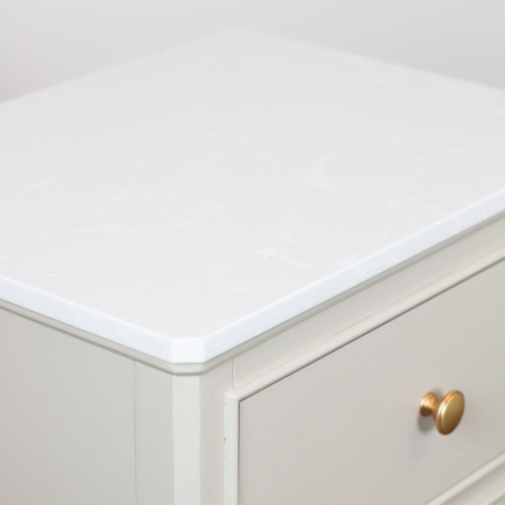 Monroe 2 Drawer Accent Table in Stone cabinet with a white countertop and gold handle.