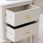 A close-up of a white two-drawer dresser with gold round knobs, showing the open top drawer and the bottom drawer partially open.