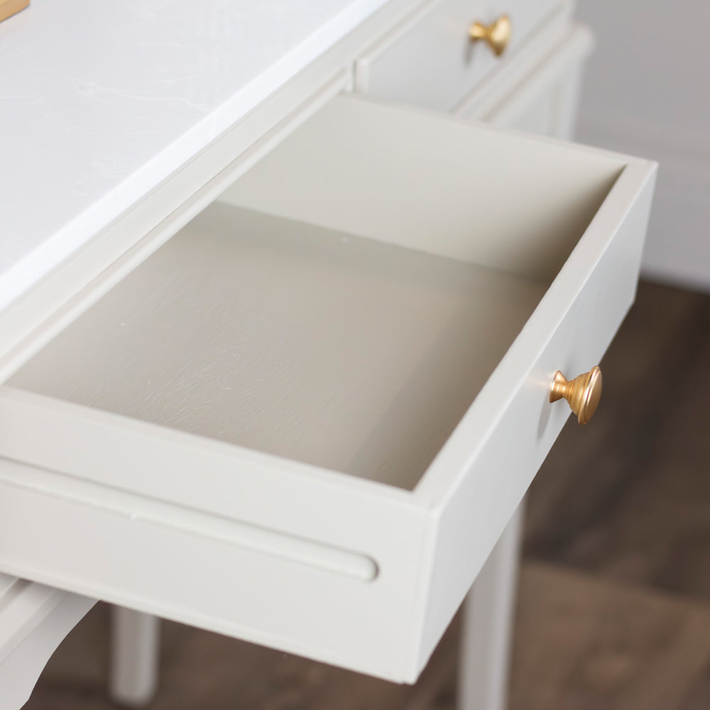 White drawer with gold knobs on a wooden floor.